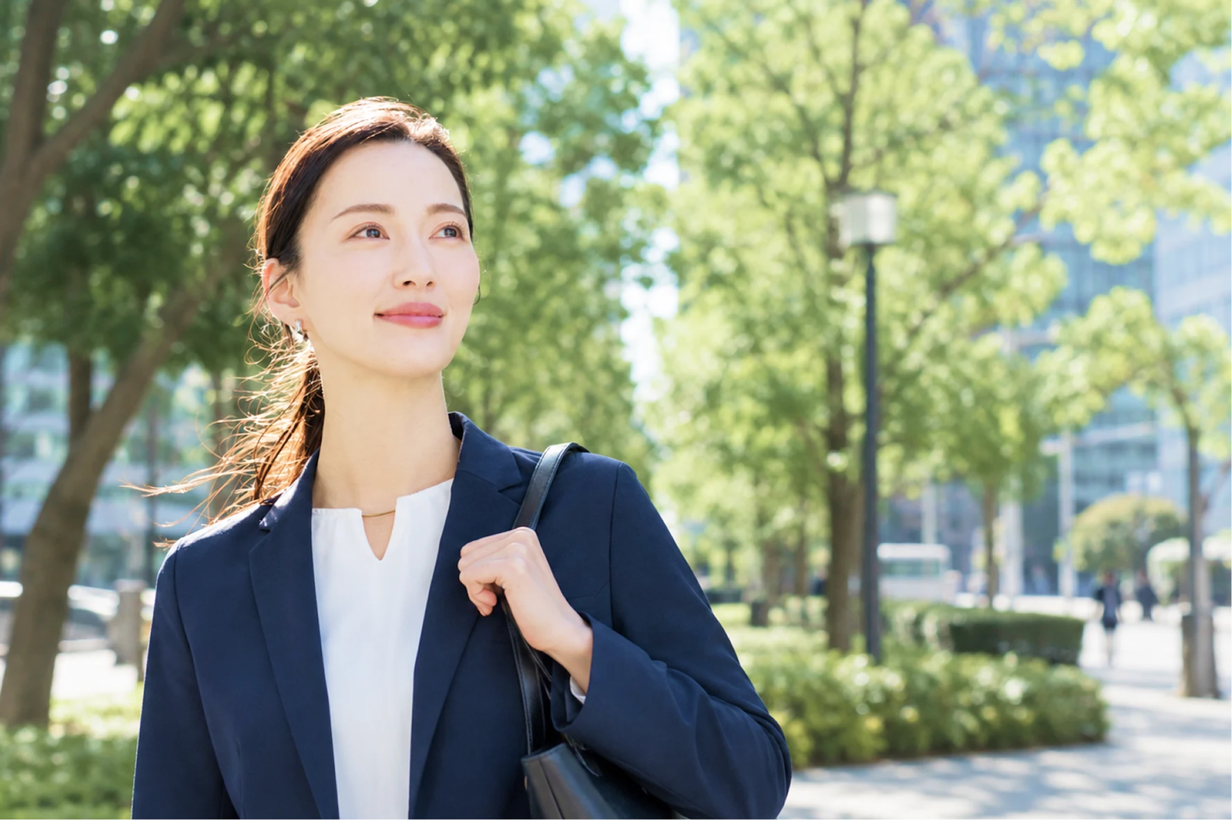 緑のある街で前を向く女性